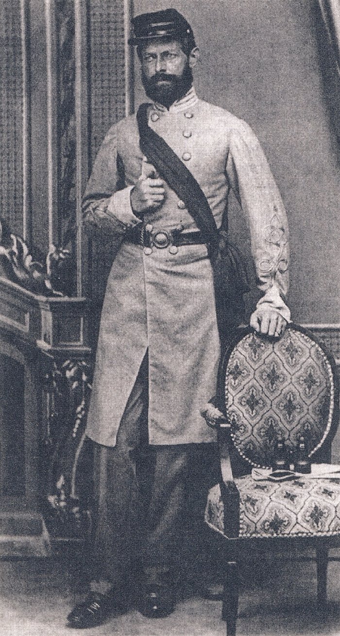 A standing studio portrait of Captain Henry Wirz in Confederate uniform, holding a cap, photographed before the war's end