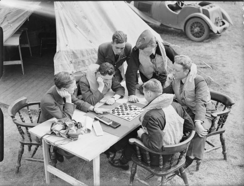 Aircrew in flying kit sitting around a table playing a board game outdoors