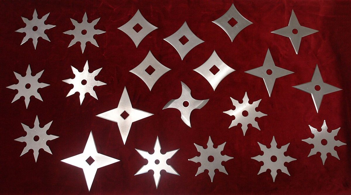 Twenty steel throwing stars of varying point counts arranged in rows on dark red velvet