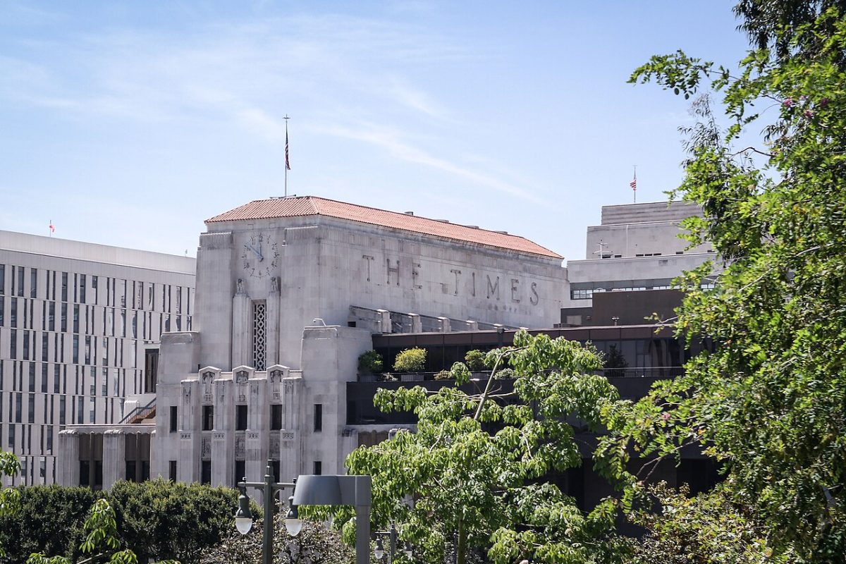 The Art Deco Los Angeles Times building in downtown Los Angeles, its name carved in stone above the entrance, seen across trees