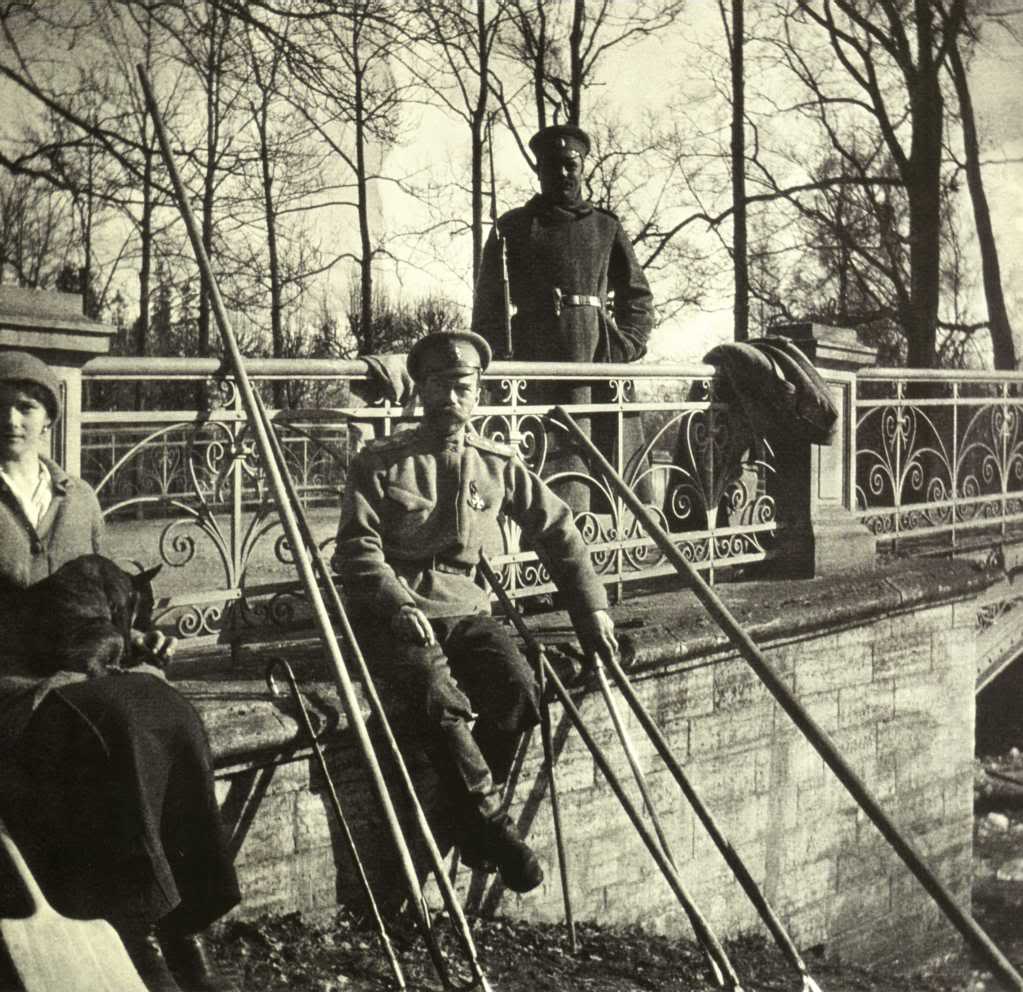 People working with garden tools in a park while a figure watches from behind railings