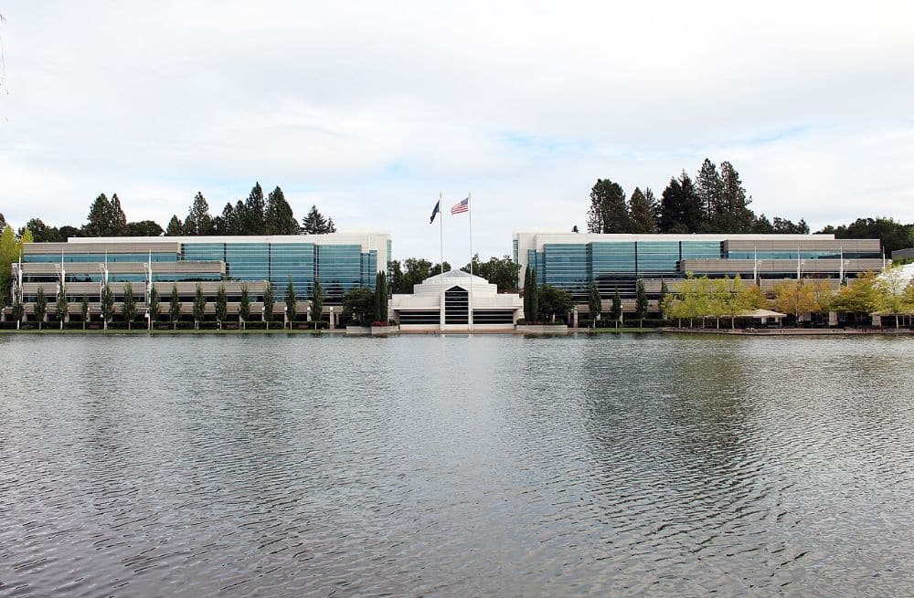 Two glass-fronted office buildings of the Nike World Headquarters campus seen across a lake in Beaverton, Oregon