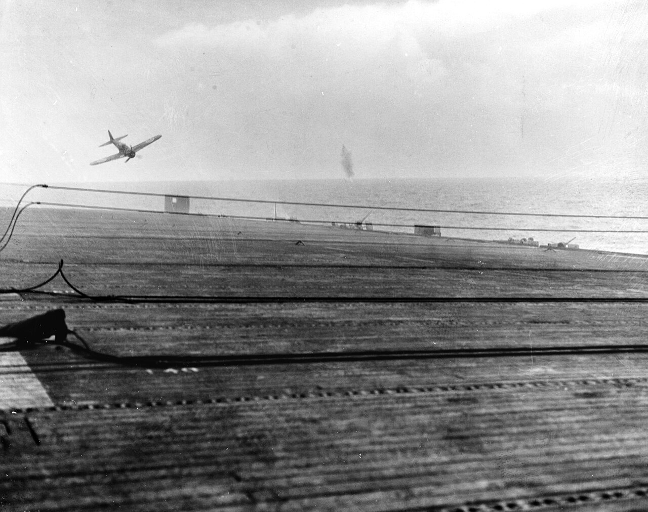 A Japanese aircraft in a steep dive toward an American escort carrier