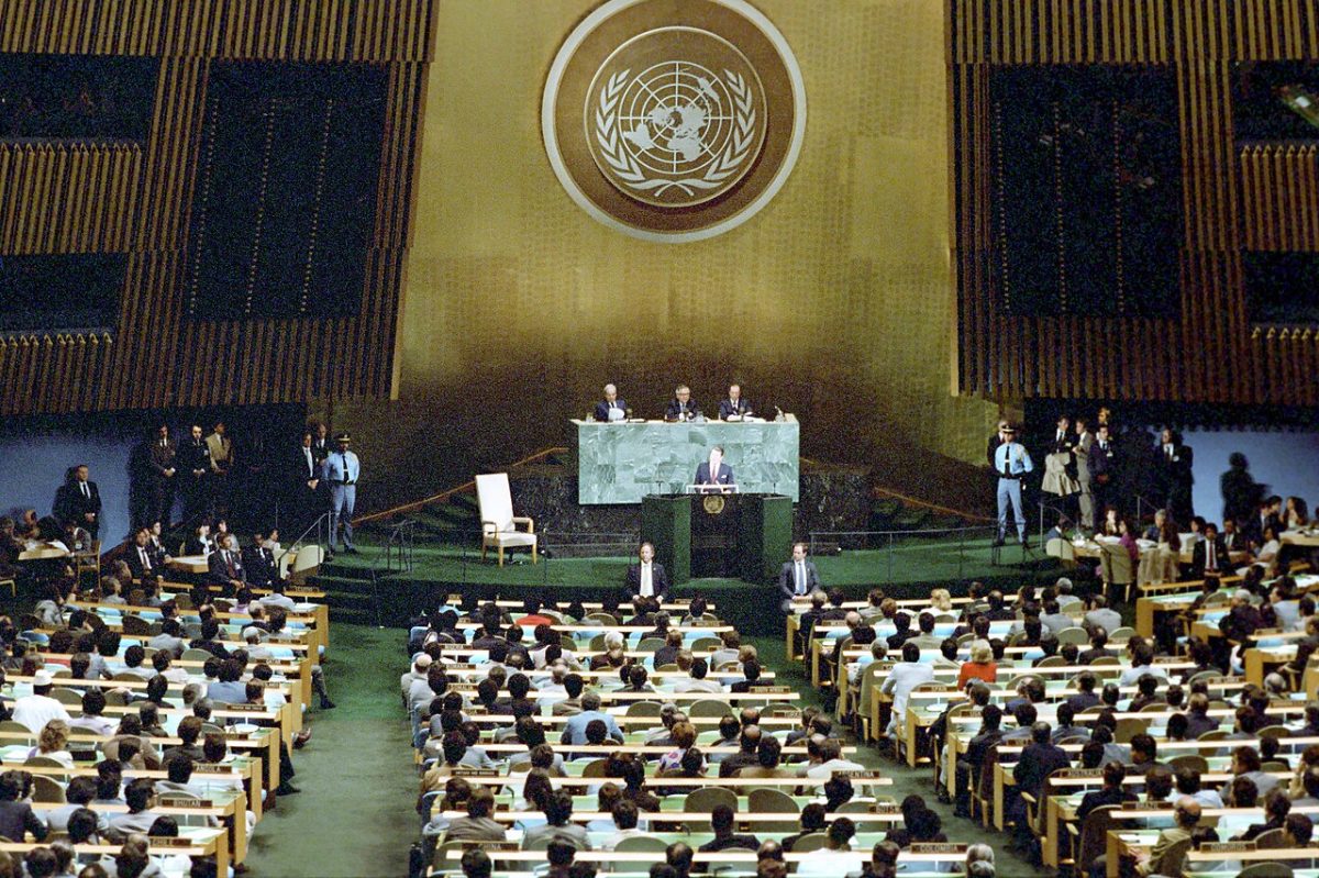 A wide view of the United Nations General Assembly hall during a Reagan address, with delegates filling the floor beneath the UN emblem