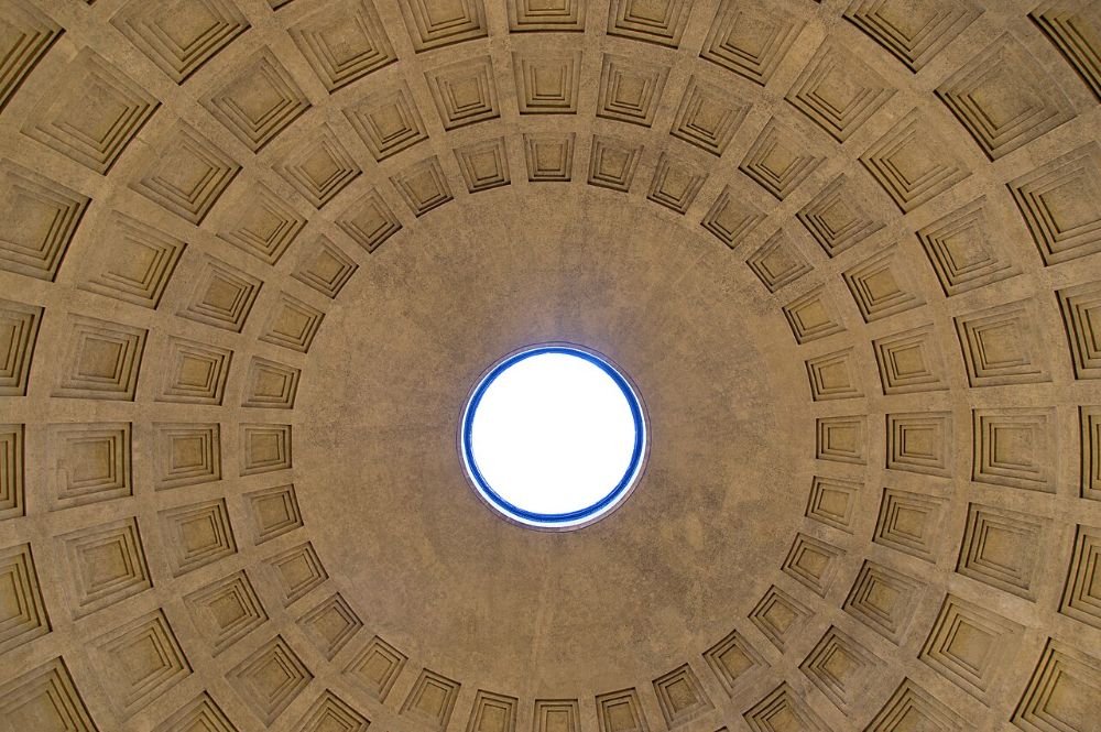 Interior of a coffered dome with a central circular opening letting in daylight.