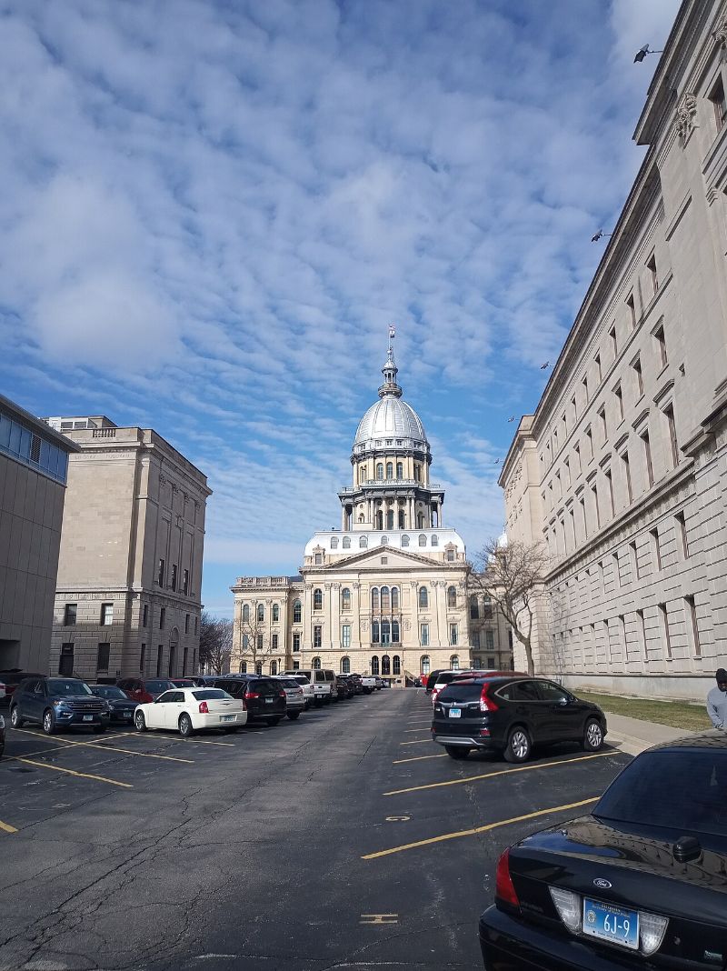 The domed Illinois State Capitol in Springfield seen down a street lined with government buildings