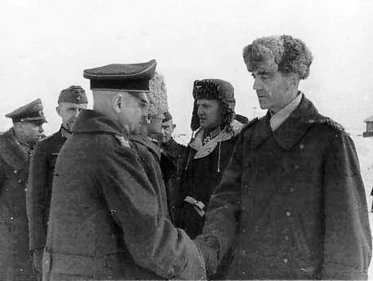 Captured German generals in greatcoats and fur hats standing together in the snow